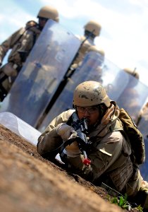 US Navy 100421-N-4965F-372 Master-at-Arms 3rd Class William Landeros, assigned to Maritime Expeditionary Security Squadron (MSRON) 3, takes cover behind a vehicle at a simulated forward operating base photo