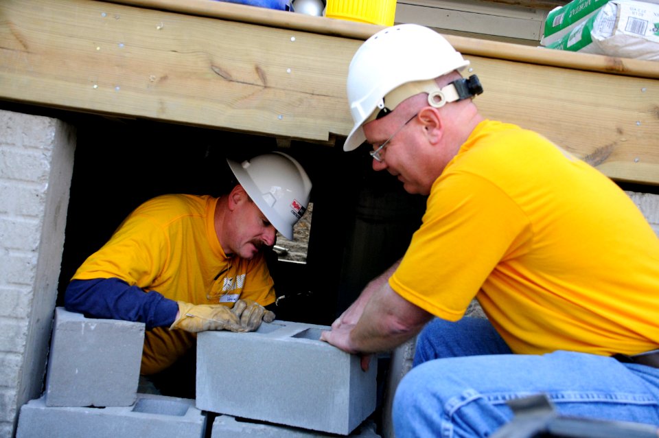 US Navy 100421-N-5366K-029 Cmdr. Matthew Brotherton, right, passes Chief Builder's Mate John Volk a breeze block at a Habitat for Humanity construction site in Des Moines, Iowa, in support of Des Moines Navy Week