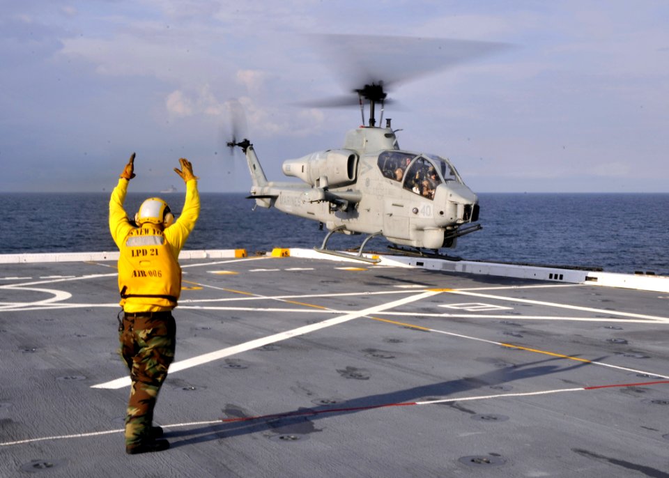US Navy 100421-N-2147L-003 Aviation Boatswain's Mate Airman Francis McCarthy directs an AH-1 Cobra helicopter, assigned to Marine Medium Tilt Rotor Squadron (VMM) 266, to land aboard the amphibious transport dock ship USS New Y