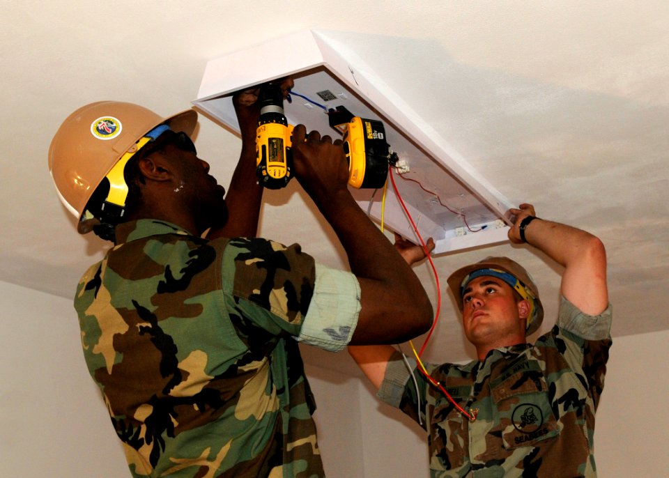 US Navy 100421-N-6357K-001 Seabees assigned to (NMCB) 7 hang a light fixture as part of the renovation of storage spaces at UCT) 1 at Naval Station Rota, Spain