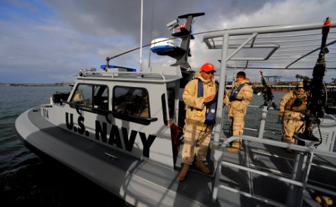 US Navy 100422-N-4965F-005 Sailors assigned to a boat detachment of Maritime Expeditionary Security Squadron (MSRON) 3 man a rigid-hull inflatable boat during a Navy Expeditionary Combat Command (NECC) integrated exercise photo