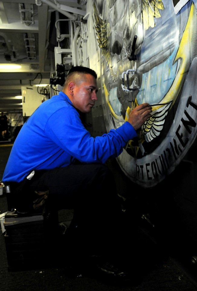 US Navy 100426-N-8913A-019 Aviation Boatswain's Mate (Handling) 2nd Class Eliseo Granado paints a door in the ship's hangar bay