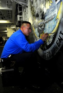 US Navy 100426-N-8913A-019 Aviation Boatswain's Mate (Handling) 2nd Class Eliseo Granado paints a door in the ship's hangar bay
