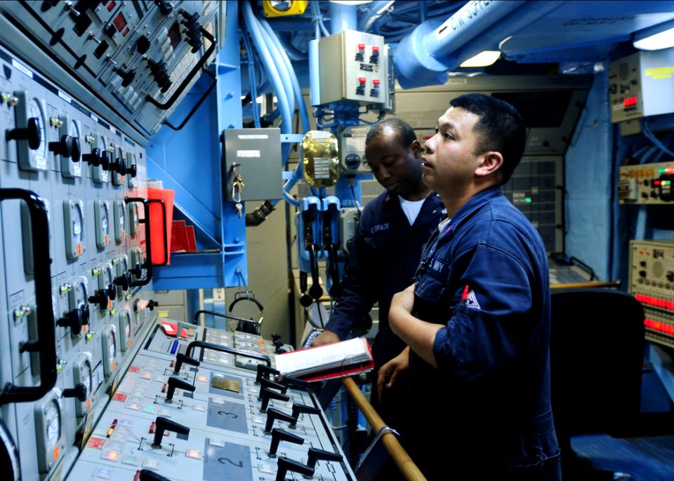 US Navy 100425-N-9301W-095 Gas Turbine System Technician (Mechanical) 2nd Class Louie Reyes, front, and Gas Turbine System Technician (Electrical) 2nd Class Christian Djiofack conduct an emergency seawater cooling valve test