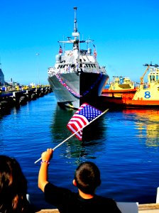 US Navy 100423-N-4774B-136 Friends and family members of Sailors aboard USS Freedom (LCS 1) wave flags and signs to greet them after completion of her maiden deployment photo