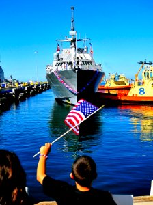 US Navy 100423-N-4774B-136 Friends and family members of Sailors aboard USS Freedom (LCS 1) wave flags and signs to greet them after completion of her maiden deployment