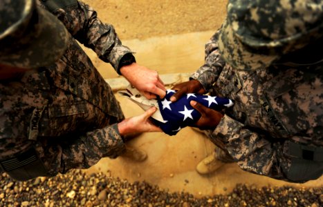 US Navy 100430-N-7130B-148 Service members assigned to Special Operations Task Force West fold an American flag during a memorial marking the anniversary of the death of Explosive Ordnance Disposal Technician 2nd Class Tyler Tr photo