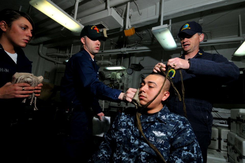 US Navy 100427-N-5749W-066 Senior Chief Hospital Corpsman Glenn Loflin demonstrates how to treat a facial wound on Hospital Corpsman 2nd Class Albert Aguilar during a medical drill and evaluation