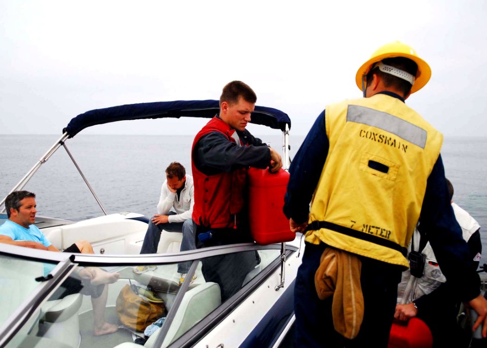US Navy 100425-N-9706M-051 Machinist Mate 3rd Class James Baker, assigned to the amphibious transport dock ship USS Dubuque (LPD 8), provides fuel to two boaters stranded off the coast of California