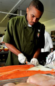 US Navy 100428-N-5812W-003 Culinary Specialist 3rd Class Corey Hartfield prepares a filet of farm-raised pacific steelhead salmon photo