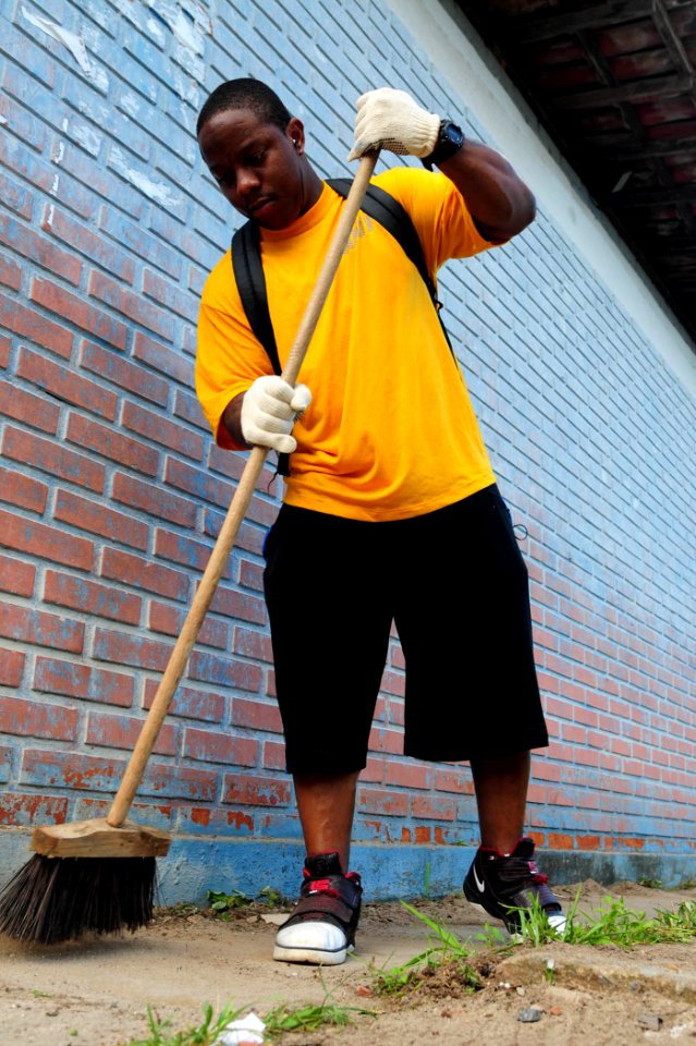 US Navy 100428-N-9301W-649 Culinary Specialist 1st Class Shon Coffie, assigned to guided-missile frigate USS Klakring (FFG 42), sweeps the walkway of the Eschol Municipal Fernando Presidio youth school as American and Brazilian