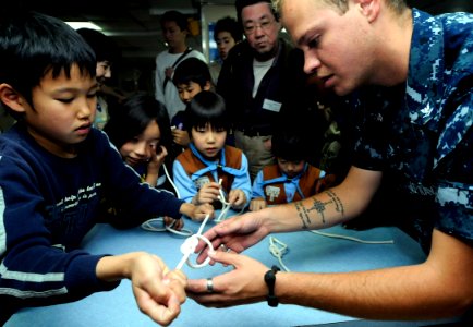 US Navy 100502-N-7280V-226 oatswain's Mate 3rd Class Jonis Birkes teaches boy and girl scouts how to tie traditional navy knots during a visit to USS Blue Ridge (LCC 19) photo