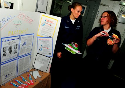 US Navy 100501-N-3595W-001 Hospital Corpsman 2nd Class Ruth Gastreich demonstrates to Aviation Boatswain's Mate 3rd Class Laura Gregg, the correct way to brush her teeth during the Women's Health Fair