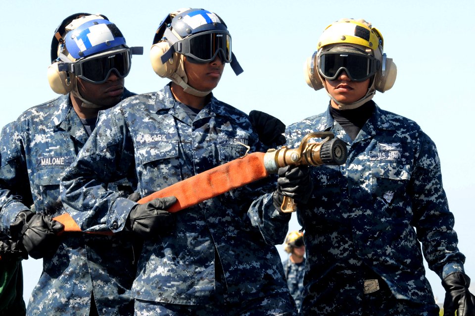 US Navy 100501-N-7605J-087 Aviation Boatswain's Mate (Handling) Airman Apprentice Dylan Malone and Aviation Boatswain's Mate (Handling) Airman Apprentice Paris Clark man a fire hose