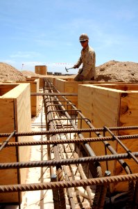 US Navy 100501-N-8936G-043 Builder 2nd Class David Harwell, from Fort Worth, Texas assigned to Naval Mobile Construction Battalion (NMCB) 7, shores up the foundation formwork of the new schoolhouse in Kontali photo