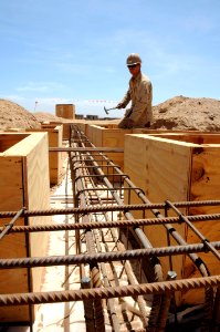 US Navy 100501-N-8936G-043 Builder 2nd Class David Harwell, from Fort Worth, Texas assigned to Naval Mobile Construction Battalion (NMCB) 7, shores up the foundation formwork of the new schoolhouse in Kontali