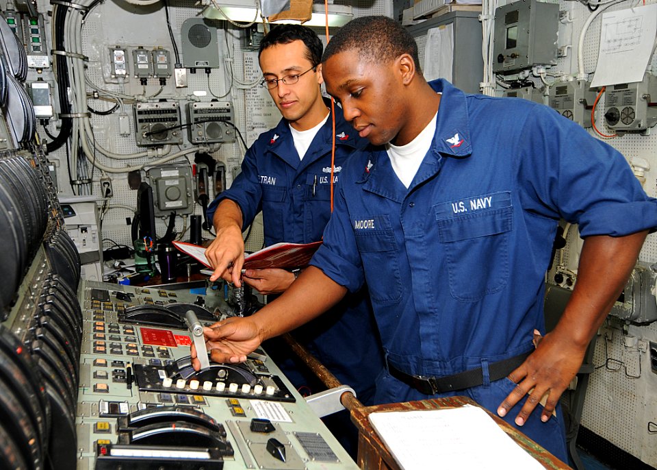 US Navy 100503-N-1082Z-022 Engineman 2nd Class Alberto Beltran-Lopez, from Bogota, Colombia, provides training on the main propulsion console to Engineman 3rd Class Marcus J. Moore, from Chicago