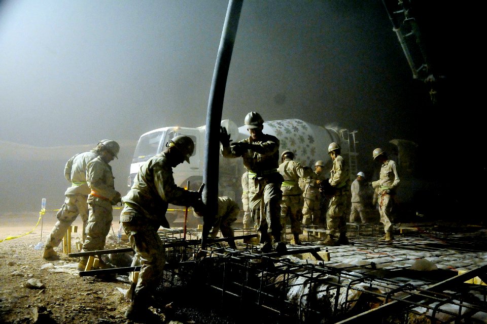 US Navy 100504-N-0475R-743 Seabees assigned to Naval Mobile Construction Battalion (NMCB) 5 pour concrete from a pump truck into the footing foundation of a KSPAN project at Camp Leatherneck, Afghanistan