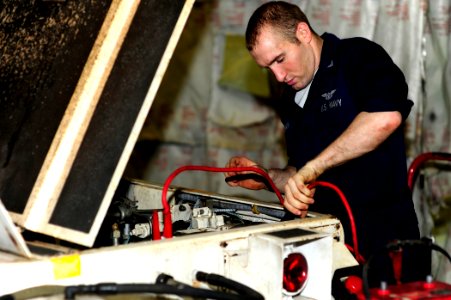 US Navy 100504-N-6604E-004 Aviation Support Equipment Technician Airman James Hillman attaches jumper cables to the battery of an aircraft tow tractor