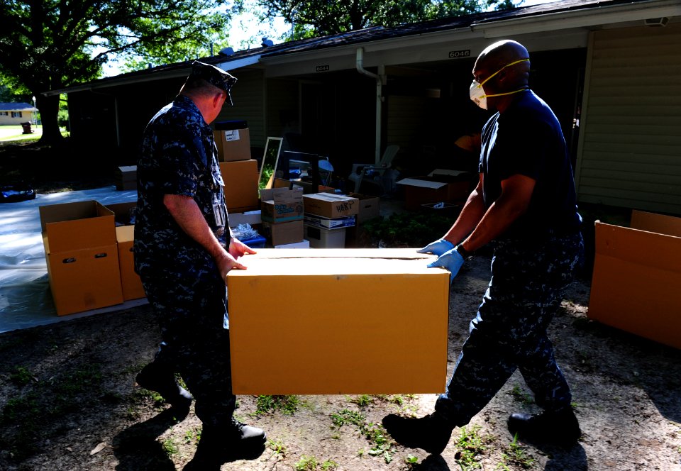 US Navy 100505-N-5862D-012 Petty Officers 1st Class Malvin Howe, left, and Christopher Caldwell volunteer to help residents of base housing at Naval Support Activity Mid-South move their possessions