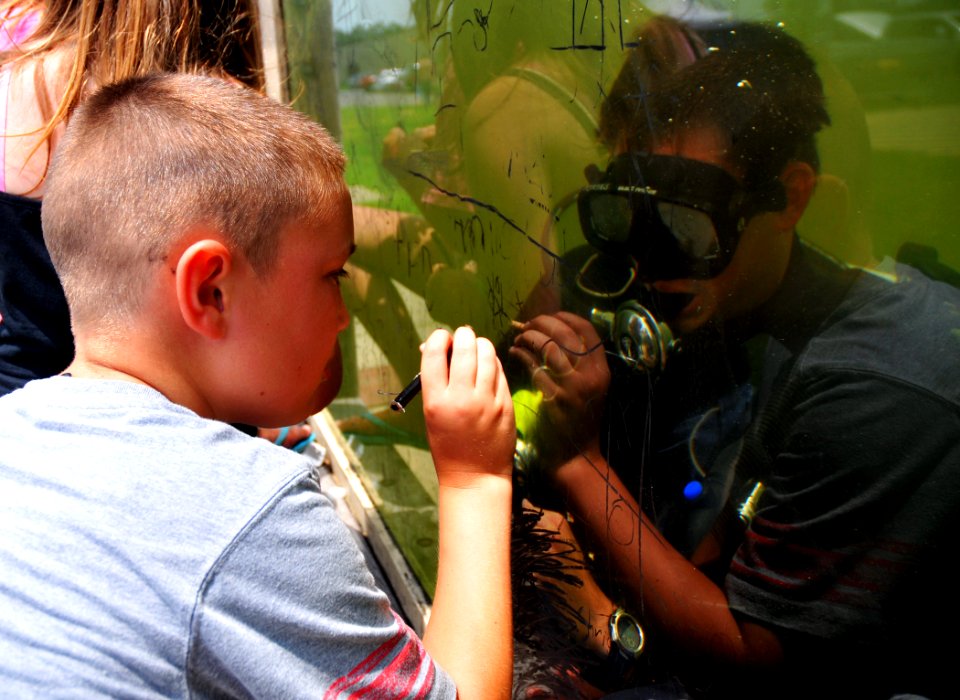 US Navy 100508-N-7367K-010 A child plays tic tac toe with a Navy diver during Seabee Day at Naval Construction Battalion Center, Gulfport