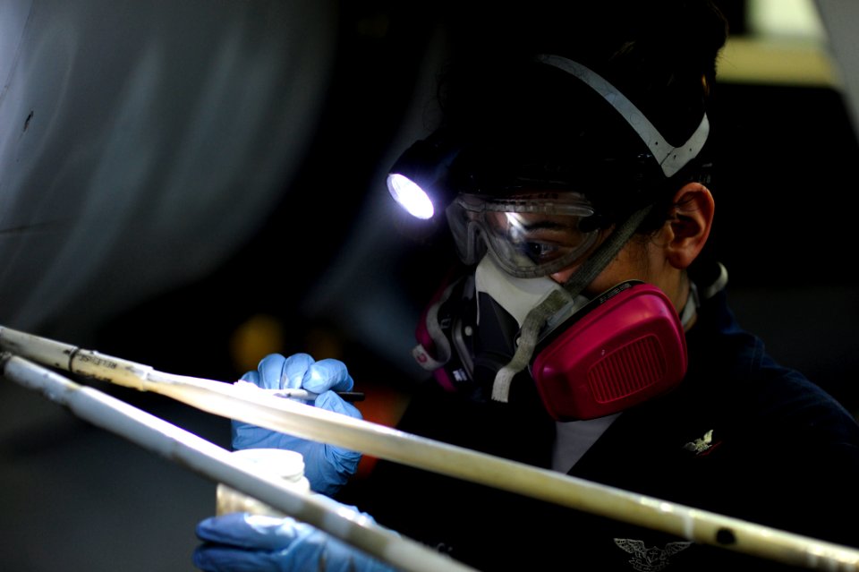 US Navy 100509-N-6604E-055 Aviation Ordnanceman 3rd Class Elizabeth Castellanos paints a ladder support bar in the hangar bay of the aircraft carrier USS Dwight D. Eisenhower (CVN 69)