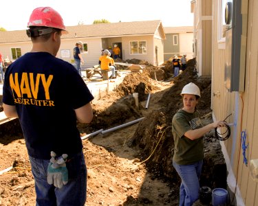 US Navy 100512-N-0869H-046 Operations Specialist 1st Class Eva Garcia, right, assigned to Navy Recruiting Station Spokane, paints one of nine housing units being constructed during a Habitat for Humanity building project photo