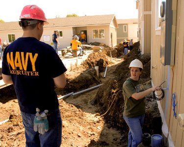US Navy 100512-N-0869H-046 Operations Specialist 1st Class Eva Garcia, right, assigned to Navy Recruiting Station Spokane, paints one of nine housing units being constructed during a Habitat for Humanity building project