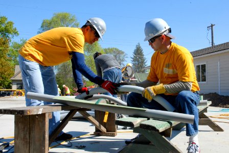 US Navy 100512-N-0869H-049 Information Systems Technician 1st Class Matt Perez and Hospital Corpsman 1st Class Devin McConnell prepare pipe for conduit installation during a Habitat for Humanity building project