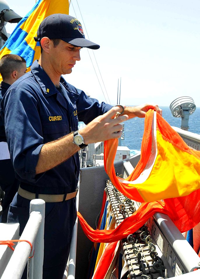 US Navy 100510-N-1082Z-109 Ensign Todd E. Coursey, from Summerville, S.C., removes a flag from the flag bag during junior officer training aboard the amphibious dock landing ship USS Ashland (LSD 48)