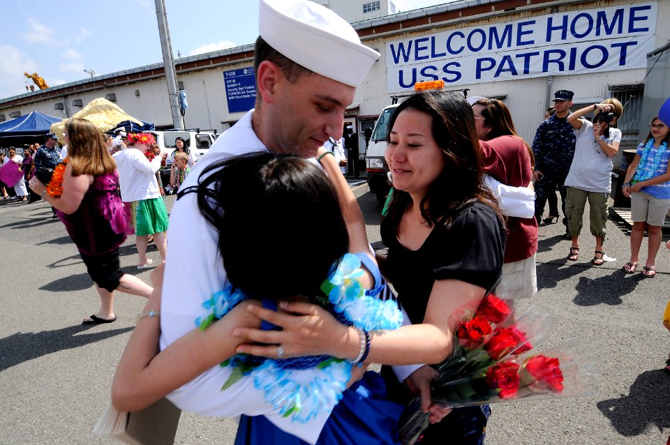 US Navy 100512-N-8335D-302 Electronics Technician 1st Class David Kelley, assigned to the mine countermeasures ship USS Patriot (MCM 7), hugs his wife and child after Patriot arrived in Sasebo, Japan