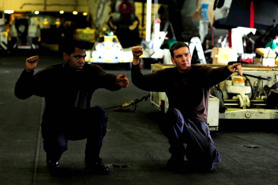 US Navy 100511-N-6604E-113 Aviation Electronics Technician Airman Gregory De Lapp demonstrates proper flight deck signals to a shipmate for pre-flight checks in the hangar bay of the aircraft carrier USS Dwight D. Eisenhower (C