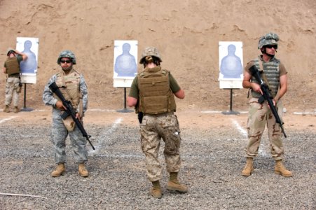 US Navy 100512-N-7526R-096 Service face away from their targets as a member of the range safety team fixes a target during a U.S. Marine Corps Enhanced Marksmanship range evolution photo