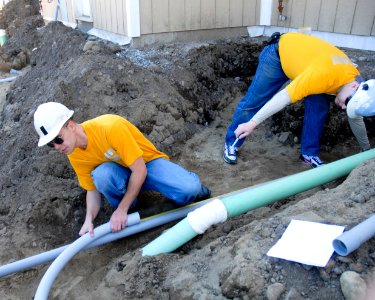 US Navy 100512-N-0869H-054 Navy Counselor 1st Class Chris Oliveria and Hospital Corpsman 1st Class Devin McConnell measure pipe for conduit during a Habitat for Humanity building project photo