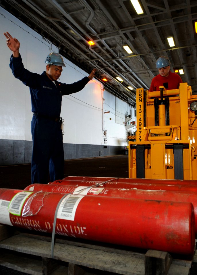 US Navy 100513-N-4516G-038 Aviation Ordnanceman Airman Apprentice Pedro Collington directs Aviation Ordnanceman Airman Jossie O. Marquez-Ruiz on a reach-and-tier electric forklift