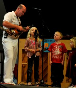 US Navy 100518-N-0773H-026 Chief Musician Patrick White assists an audience member from Carroll Manor Elementary School in a performance On Grandpa's Farm