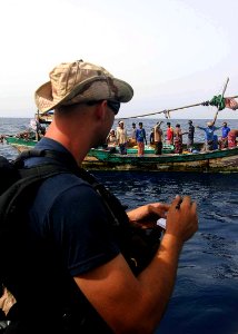 US Navy 100519-N-1082Z-014 Gunner's Mate 3rd Class Justin L. Myers takes notes as the team visits with fishing dhows while conducting maritime security operations photo