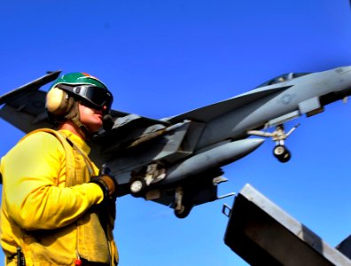 US Navy 100515-N-6935K-001 An arresting gear officer aboard the aircraft carrier USS Dwight D. Eisenhower (CVN 69) observes flight deck operations as an F-A-18F Super Hornet lands
