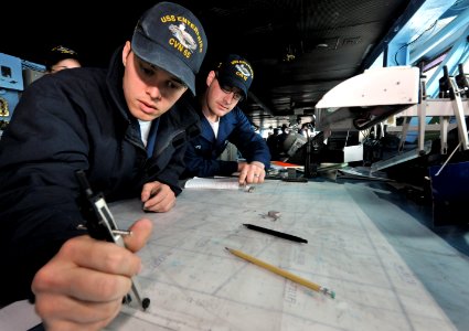 US Navy 100517-N-4516G-002 Quartermaster Seaman Zachary W. Hollis uses a compass to plot the ship's position on an operational-area chart while Quartermaster Seaman Bobby L. Boyd observes aboard USS Enterprise (CVN 65)