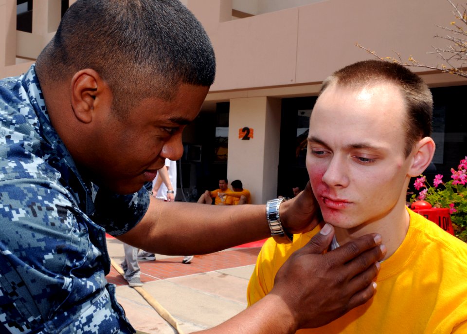 US Navy 100518-N-6326B-032 Hospital Corpsman 1st Class Ricardo A. Blake assesses facial burns and abrasions on the face of Hospital Corpsman Seaman Patrick T. Mesey during the annual statewide Golden Guardian drill