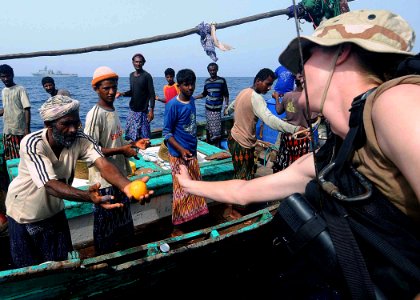 US Navy 100519-N-1082Z-038 Boatswain's Mate Seaman Shana M. Kemerling passes fresh fruit to a fishing dhow crew member as the team visits with the boat while conducting maritime security operations photo