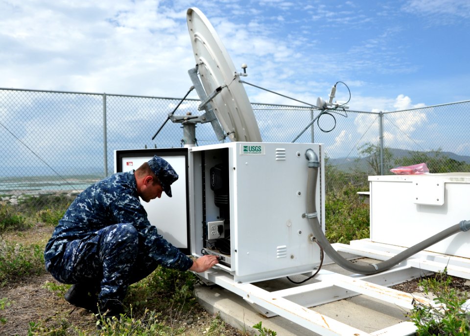 US Navy 100518-N-8241M-021 Electronics Technician 1st Class Michael Schiltz, assigned to Naval Station Guantanamo Bay (GTMO), Cuba, adjusts a modem on a U.S. Geological Survey (USGS) remote seismic station