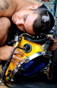 US Navy 100522-N-0413B-140 Navy Diver 3rd Class Wilson Cordoba, assigned to Mobile Diving and Salvage Unit (MDSU) 1, listens for air in a MK-3 dive helmet