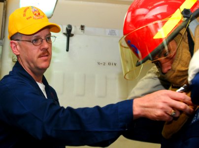 US Navy 100522-N-1092P-010 Logistics Specialist 2nd Class Terry Bevill helps a Sailor with his flash gear during a general quarters drill aboard the Arleigh Burke-class guided-missile destroyer USS Winston S. Churchill (DDG 81)