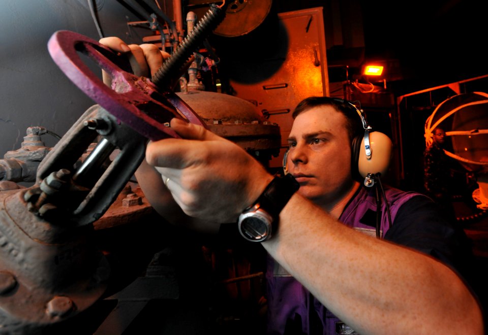 US Navy 100522-N-4516G-007 Aviation Boatswain's Mate (Fuels) Airman Jeffrey A. Schubert opens a gate-valve discharge to fuel an F-A-18 Hornet engine for a test cell engine run aboard the aircraft carrier USS Enterprise (CVN 65)