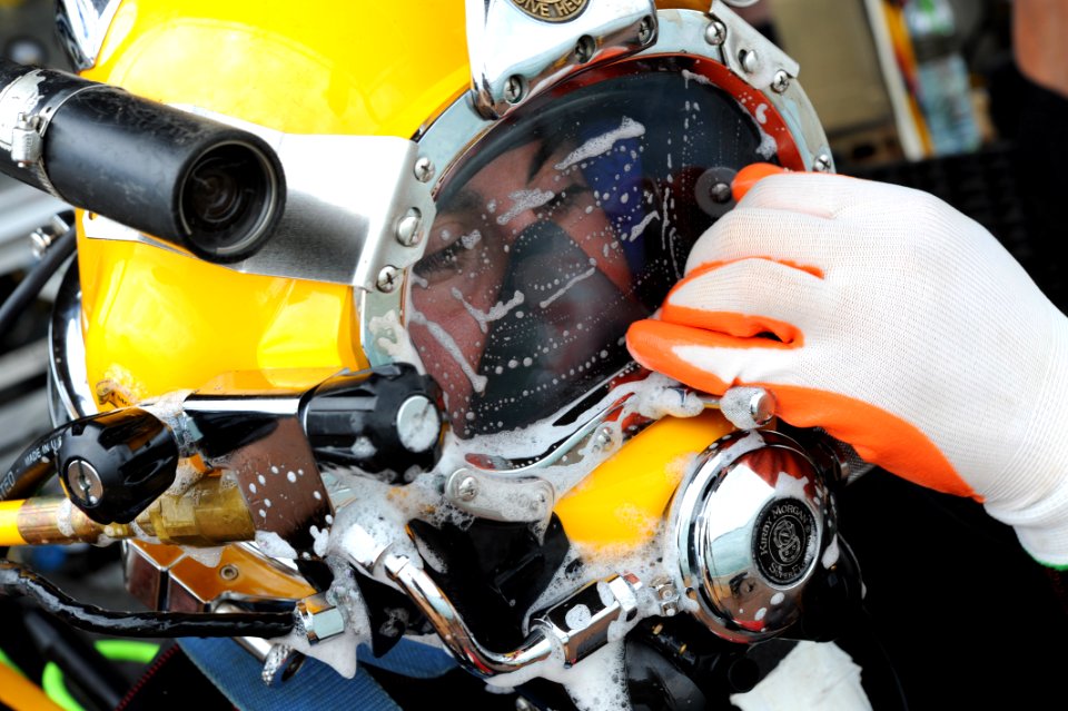US Navy 100527-N-0413B-008 Navy Diver 2nd Class Jessie Trujillo, assigned to Mobile Diving Salvage Unit (MDSU) 1, wipes off cleaning soap from his MK-3 dive helmet glass during pre-dive checks during the Joint POW-MIA Personnel