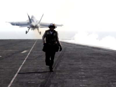 US Navy 100523-N-4236E-260 A Sailor walks along the flight deck as an F-A-18F Super Hornet assigned to the Jolly Rogers of strike fighter squadron (VFA) 103 launches from the aircraft carrier USS Dwight D. Eisenhower (CVN 69)