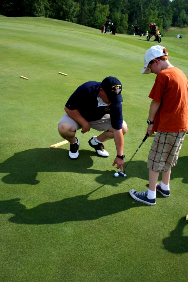 US Navy 100525-N-6220J-279 Chief Navy Career Counselor Steven Polach, zone 9 Supervisor for Navy Recruiting, gives putting advice to a young First Tee participant at the First Tee of Central Arkansas during Little Rock Navy Wee