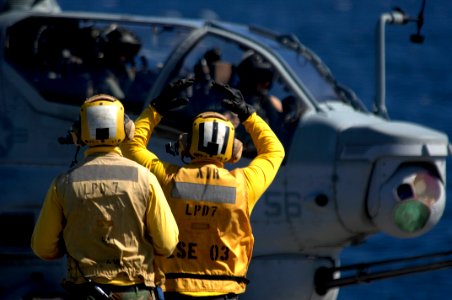 US Navy 100524-N-6477M-251 Aviation Boatswain's Mate Airman Apprentice Micah Bogstadt, right, shadowed by Aviation Boatswain's Mate Airman Rodney Crowley, gives the signal for lift off to an AH-1Z Super Cobra