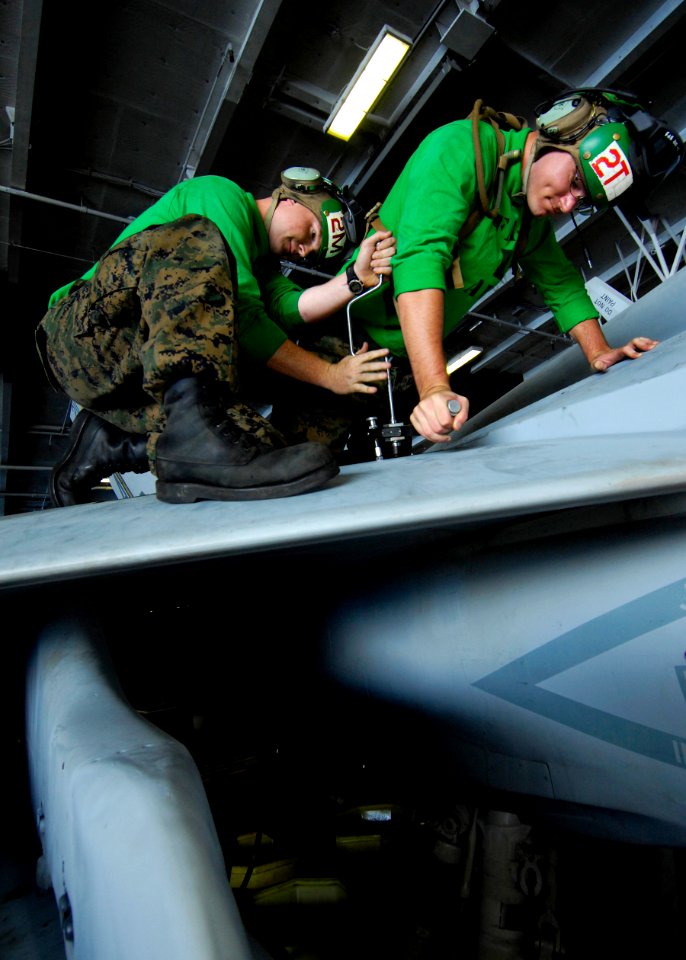 US Navy 100525-N-6362C-104 Hydraulic and structural mechanical Cpl. Daniel Schaefer and avionics technician Cpl. Brian Vaughn perform maintenance on the wing of an F-A-18C Hornet
